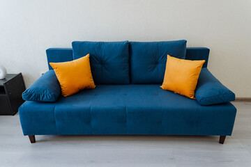 In a cozy living room, there is a striking blue couch adorned with vibrant yellow pillows, creating a cheerful and inviting atmosphere that is perfect for relaxation and comfort
