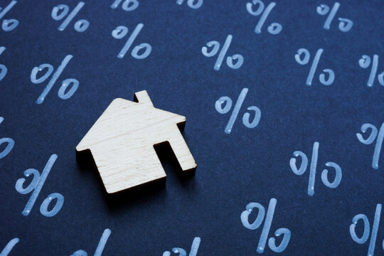Home loan interest rates and real estate investment. Model house and percentage signs.
