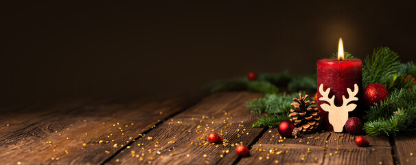 Red Candle with Christmas decoration on rustic wood - Advent Background with wreath on first Advent...