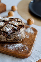 On a sturdy wooden cutting board, a freshly baked loaf of bread is resting, ready to be sliced and...