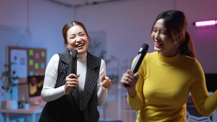 Joyful office colleagues singing and laughing together in karaoke session