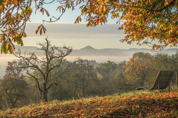 Holzliege mit herbstlicher Aussicht auf Panorama der schw&auml;bischen Alb mit Achalm und Nebel im Tal  bei Sonnenaufgang zwischen Altenriet und Neckartenzlingen.