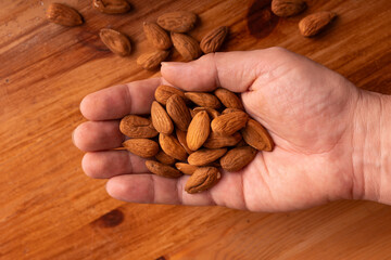 Human hand holding fresh organic almonds wooden table healthy natural protein food