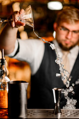 Selective focus of martini glass with male bartender pouring crushed ice
