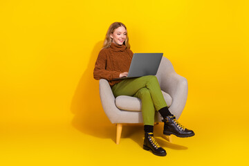 Full body portrait of nice young girl sit chair use laptop isolated on yellow color background