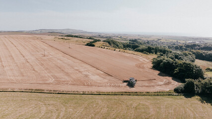 Obraz premium Aerial view of a huge farm land and a combined harvester harvesting the farm 