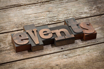 events, word written with vintage letterpress printing blocks, angled view, rustic wooden background