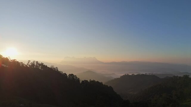 Hipster male hiker with backpack standing on mountain enjoying sunrise with mist background. Hiker men's hiking living healthy active lifestyle.