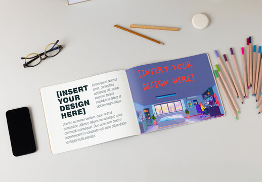 Customizable mockup of Notebook Laid Open on a Desk With Stationery and Phone. Overhead view.