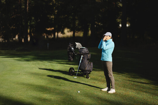 Female golfer looks into rangefinder and measures distance