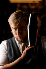 Close-up of a male bartender holding a shaker with both hands near his face