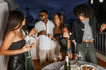 Chic multi-ethnic friends partying in a rooftop at night
