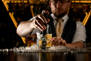On the bar counter, in the middle of a pile of crushed ice, there is a glass with a lemon cocktail