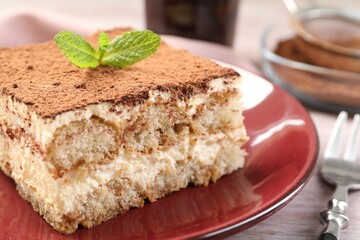 Delicious tiramisu with mint on light wooden table, closeup