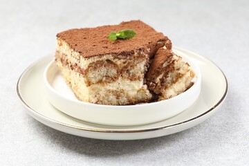 Delicious tiramisu with mint on light table, closeup