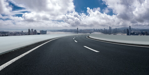 Fototapeta premium Scenic Urban Roadway Leading to a Vibrant City Skyline Under Dramatic Clouds