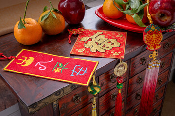 Close up of Chinese New Year good fortune, well being decorations with tangerines and red apples on a wooden chest. A Lunar New Year concept, background.