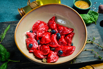Dumplings with cherries, raspberries and salted caramel. On a black stone background. In a plate, close-up.