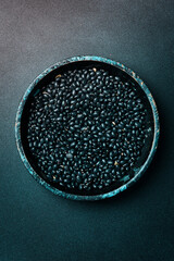 organic black beans in a wooden bowl. Zero waste storage concept. On a dark background.