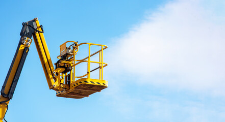 Elevated work platform extends towards blue sky at construction site during bright sunny day