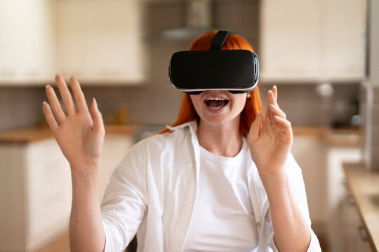 Woman enjoying virtual reality experience at home with excitement and engagement in modern kitchen setting