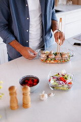 Partial view of african american man cooking healthy dinner with chicken and fresh salad in kitchen