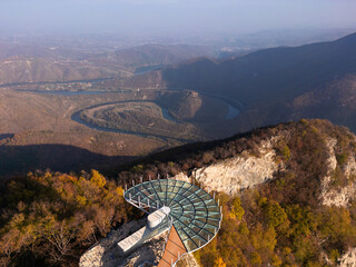 Aerial scenic view of modern and futuristic glass skywalk viewpoint, extending over mountain Ovcar and Kablar canyon in Serbia. Meanders of West Morava river. Ovcarsko-Kablarska gorge.