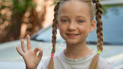 Adorable happy Caucasian cute little child kid school girl positive pupil looking at camera smiling schoolgirl showing ok gesture okay sign good recommend at city street soap bubbles. Adoption custody