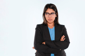 Confident young woman wearing glasses and a blazer with crossed arms, expressing determination against a simple background