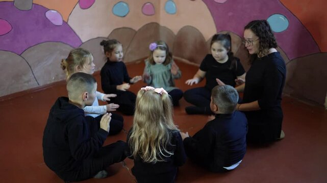 5-7 year old children sit in a circle at an acting class, extracurricular activities