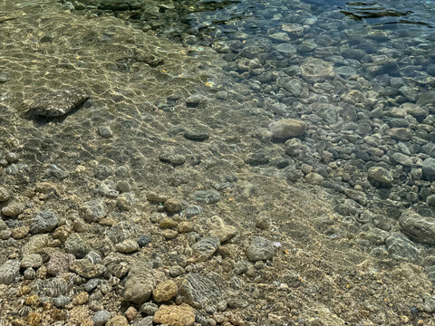 Smooth stones pebbles in clear water on sea shore