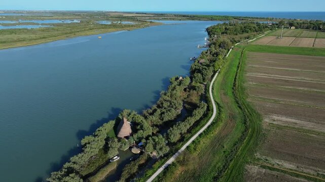 aerial reveal of the Nicesolo canal fishing community using traditional Venetian reed construction called Casoni di Caorle, Caorle, Italy