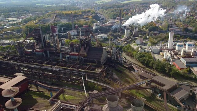 Trinec industrial district showing factory and smokestacks, Czech Republic, high angle aerial pullback over chutes and tubes above train tracks