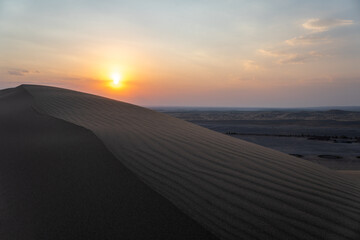 The vibrant sun is slowly setting over a vast desert landscape, Kashan, Iran