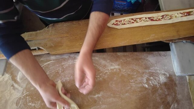 The pide maker places the pitas on a wooden oven shovel to bake. Turkish-style pizza.
