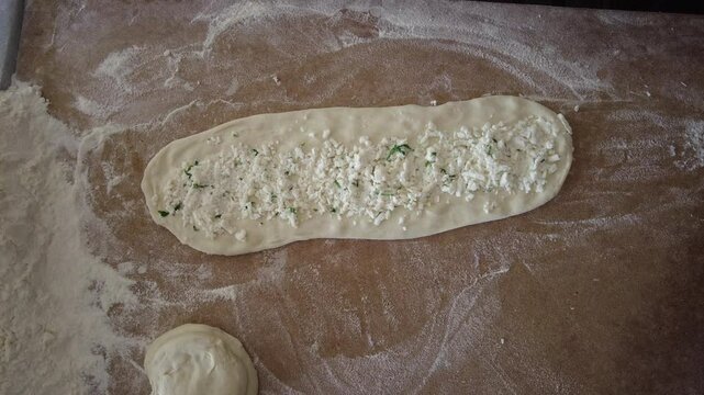 The pide maker puts cheese on the dough to be baked in the oven. Turkish-style pizza.

