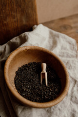 A wooden bowl of dry tea leaves with a wooden spoon. Tea for fermented kombucha with probiotic
