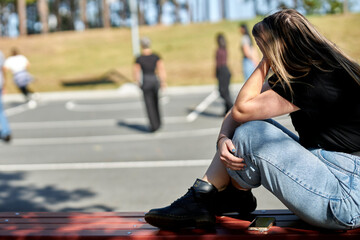 Female ostracized from group, left alone from friends. Mental health, introversion and sadness shown. Actress portraying mental illness, depression, anxiety, eating disorder, ADHD, or other mental ill