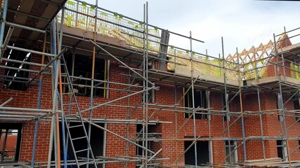 Construction of new residential building in urban area showcasing brickwork and scaffolding during afternoon hours