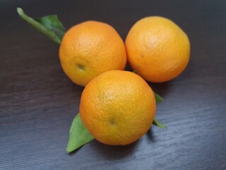 A beautiful branch of orange ripe tangerines lies on a rustic surface