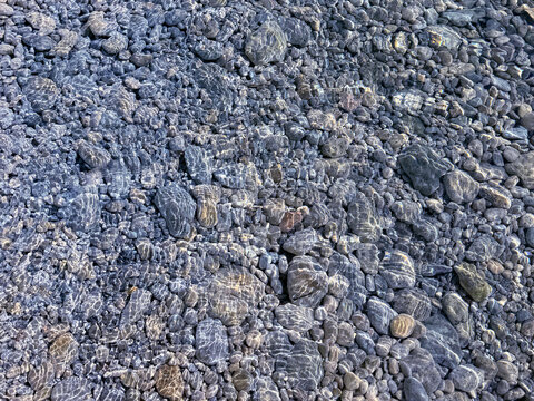 Beautiful stones pebbles in clear transparent sea water natural background.
