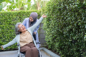 Muslim female doctor caregiver assisting elderly patient in wheelchair, healthcare service, senior...