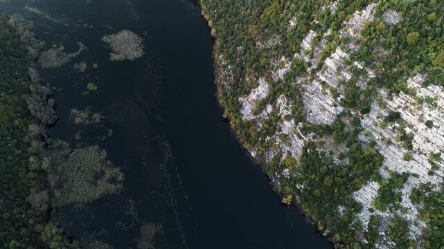 Rijeka Crnojevica river near Skadar lake in Montenegro. A winding river among the rocky mountains. Breathtaking landscape aerial top view. Yellow-green deciduous forest from a bird's-eye view