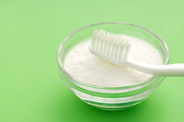 Baking soda in bowl and toothbrush - Green background.