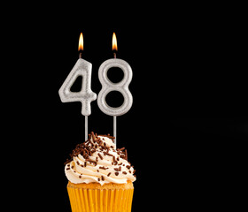 Birthday cupcake on black background - Number 48 shaped candles.