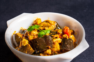 Homemade spicy aubergine curry with onions and tomatoes, in a serving bowl.