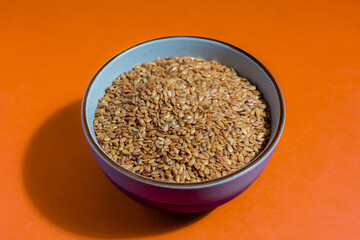 Golden linseed with sweet nutty flavour in a bowl on an orange worktop.