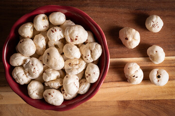 Popped lotus seeds., makhama, high in medicinal value, in a bowl on wooden worktop. High in magnesium and low sodium content.