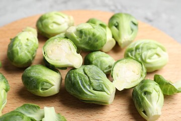 Fresh Brussels sprouts and wooden board on grey table, closeup