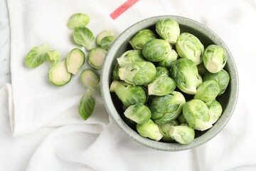 Fresh Brussels sprouts in bowl on white table, top view